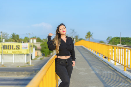 Portrait of young woman with positive attitude on a pedestrian bridge. Sunset with blue sky.の写真素材