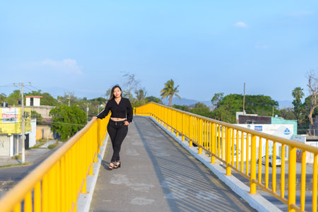 Portrait of young woman with positive attitude on a pedestrian bridge. Sunset with blue sky.の写真素材