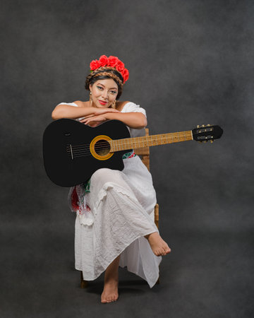 Mexican woman with guitar wearing white dress. Studio portrait.の写真素材