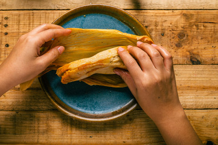 Person opening a tamale with his hands. Tamale, typical Mexican food.の写真素材