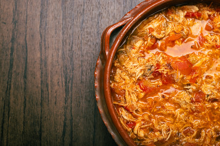 Authentic mexican chicken tinga, typical mexican food prepared in a clay pot on a wooden table.の写真素材