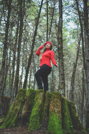 Woman with positive attitude on a mossy tree stump in the middle of the forest.の写真素材