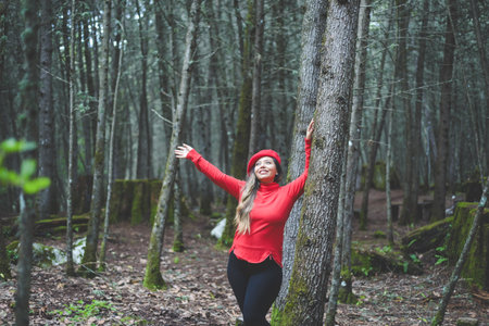 Woman with a pensive attitude admiring the forest leaning against a tree trunk.の写真素材