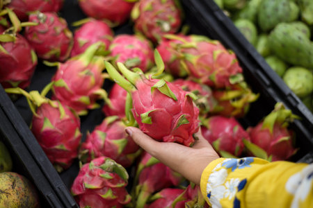 Person holding a pitaya in a supermarket. Selling dragon fruit in a market.の写真素材