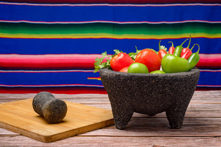 Molcajete with vegetables on wooden table. Ingredients for a hot sauce.の写真素材