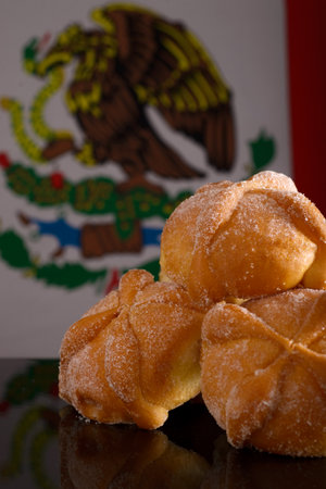 Dead bread on black glass table with mexican flag in the background. Typical dessert of the day of...