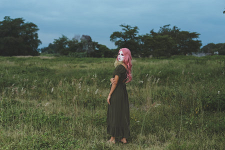 Young woman made up as a sad clown in a lonely field. Concept of loneliness and sadness. Outdoor portrait.の写真素材