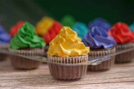 Multicolored cupcakes on wooden table. Colorful desserts.の写真素材