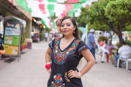 Street portrait of Mexican woman wearing traditional dress with multicolored embroidery. Hispanic woman celebrating independence day.の写真素材