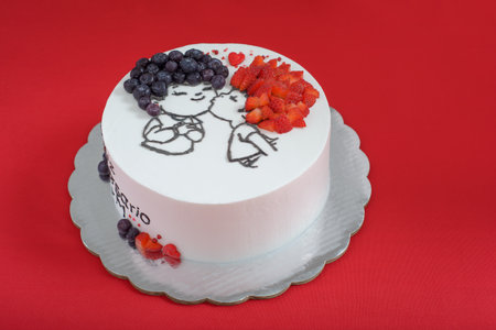 White cake decorated with drawing and red fruits. Beautiful white cake on red background.の写真素材