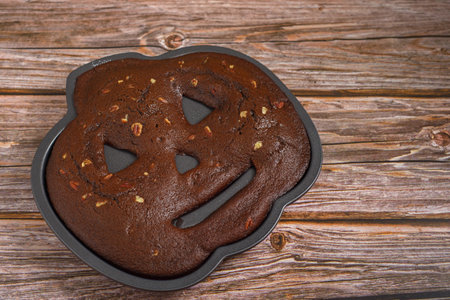 Chocolate cake with walnuts in the shape of a pumpkin lantern. Freshly baked halloween cake close up.の写真素材