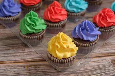 Multicolored cupcakes on wooden table. Colorful desserts.の写真素材