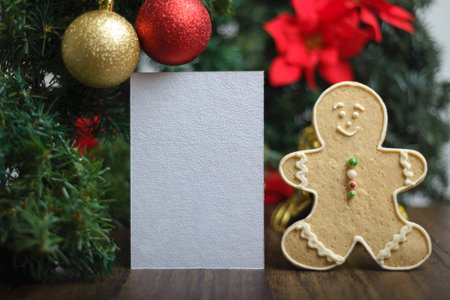 Blank card next to gingerbread man cookie and ornaments on a Christmas tree. Christmas background, selective focus.の写真素材