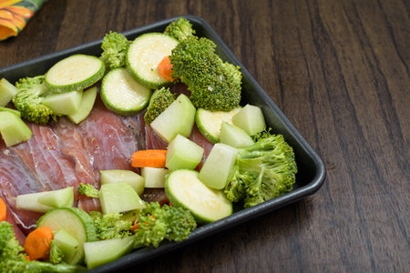 Tray with raw fish fillets and vegetables on wooden table. Healthy food.の写真素材