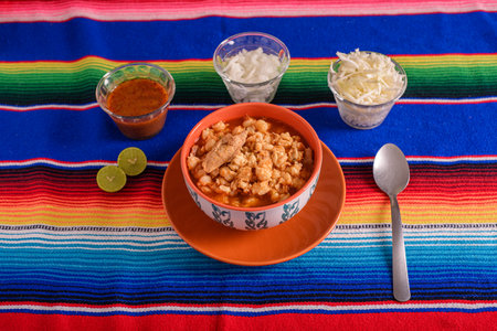 Red pozole served in a deep dish on colorful serape. Typical Mexican food made from cornの写真素材