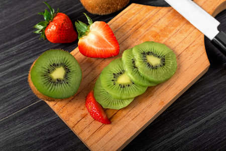 Cut fruits on a wooden board. Cut kiwi and strawberries.の写真素材