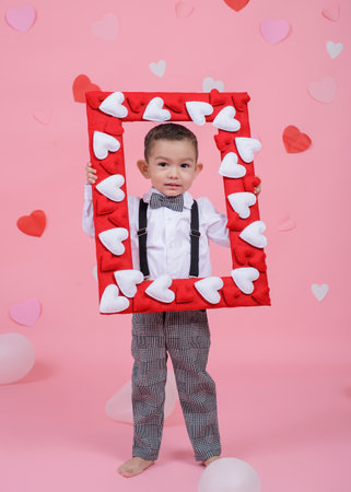 Child holding a rectangular frame with hearts. Valentine's day background with balloons in the shape of hearts.の写真素材