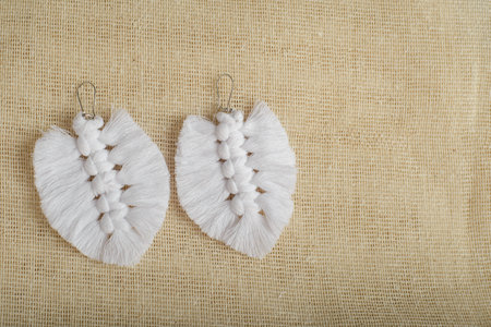 Earrings made with thread on a textile background. Handmade earrings.