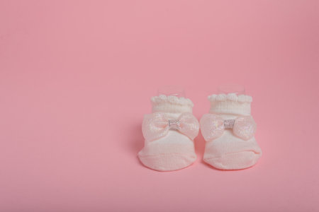 Newborn socks with bow on pink background. Copy space.の写真素材
