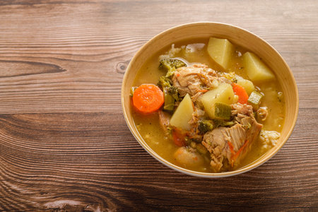 Chicken soup with vegetables in a deep bowl on a wooden table.の写真素材