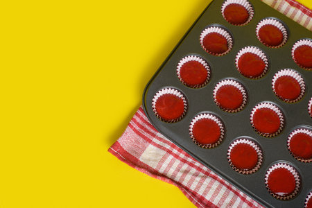 Tray with mix of red velvet cupcake ingredients ready to bake. Yellow background.の写真素材