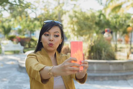 Woman in a public park taking a selfie. Sunny day.