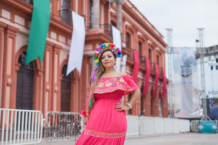 Mexican woman wearing traditional dress. Street decorated with colors of the Mexican flag. Cinco de Mayo celebration.の写真素材