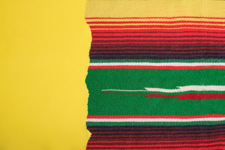 Yellow scrap paper on colorful serape. Empty template for text, Cinco de Mayo background.の写真素材