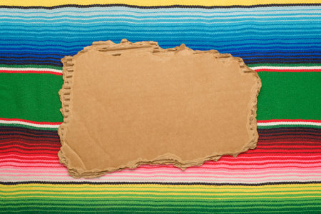 Torn cardboard on colorful serape. Space for text, Cinco de Mayo background.の写真素材
