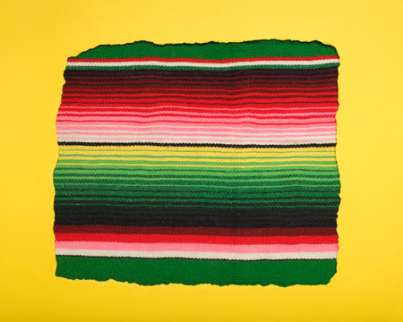 Yellow scrap paper on colorful serape. Empty template for text, Cinco de Mayo background.の写真素材