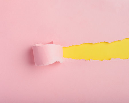 Torn pink paper revealing yellow background. Background, paper texture.の写真素材