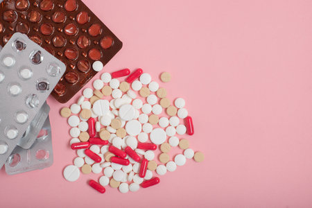 Empty drug blister packs and pills on pink background. Empty space for text.