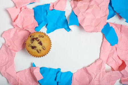 Cupcake on torn pieces of pink and blue colored paper. Space for text.