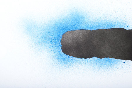 White torn paper painted with blue spray paint revealing black painted background. Space for text.