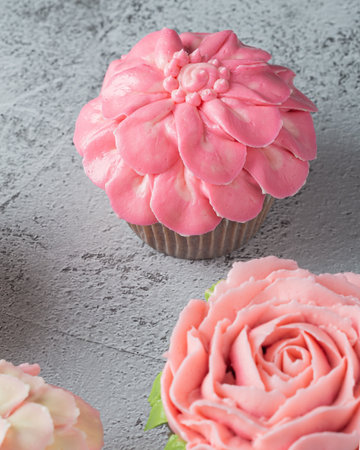 Colorful cupcakes with flower shaped decorations made with buttercream frosting.の写真素材