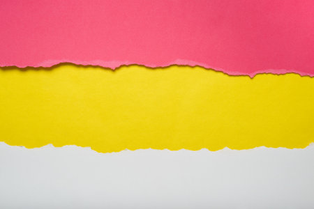 Torn pieces of red and white paper on yellow background. Torn edges.の写真素材