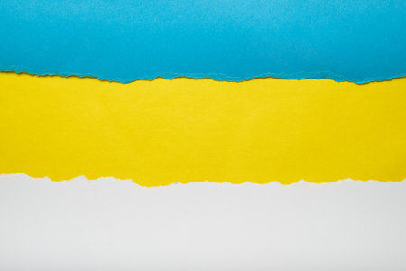 Torn pieces of blue and white paper on yellow background. Torn edges.の写真素材