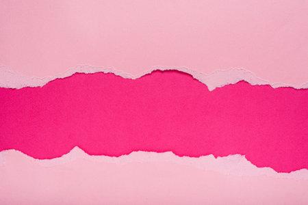 Torn pink paper on dark pink background. Space for text.の写真素材