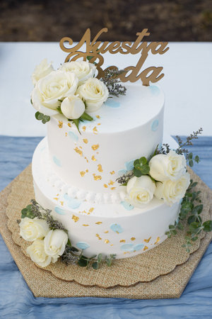 Beautiful wedding cake on an outdoor table. Cake topper with text Our Wedding written in Spanish.