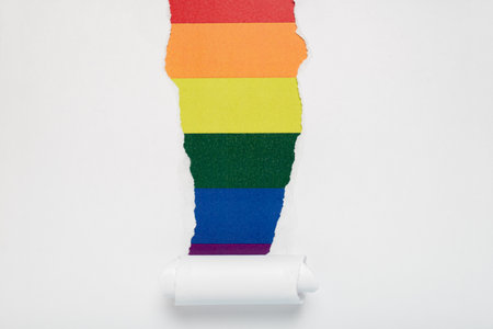 Torn hole in white paper revealing the LGTBQ flag. Rainbow flag.の写真素材