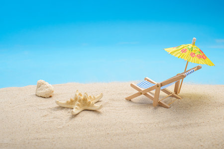 Summer background with sea sand, cocktail umbrella, starfish and beach chair. Space for text.の写真素材