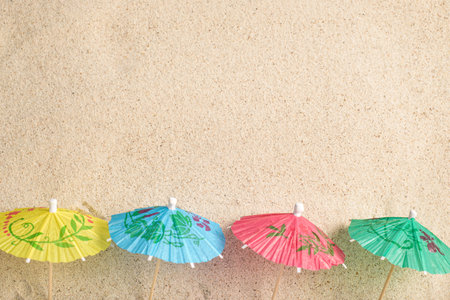 Colorful cocktail umbrellas on sea sand. Vacation concept. Summer background.