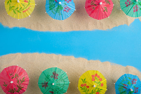 Colorful cocktail umbrellas on sea sand. Vacation concept. Summer background.