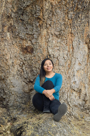 Portrait of a woman leaning on a tree trunk.の写真素材
