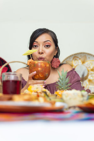Woman holding a glass of shrimp cocktail surrounded by fish dishes.の写真素材