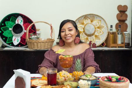 Woman holding a glass of shrimp cocktail surrounded by fish dishes.の写真素材