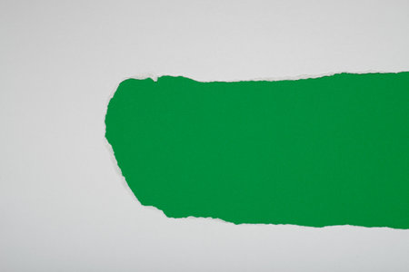 Torn white paper revealing a green background. Space for text.の写真素材