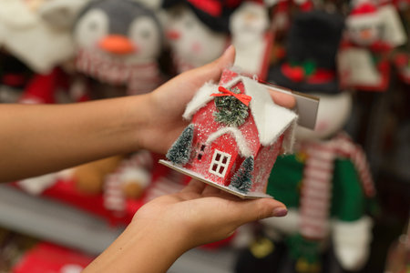 Female hands holding a Christmas tree decoration in a store. Christmas decorations for sale.の写真素材