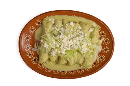 Green enchiladas with lettuce and cheese served in a clay dish. Close up.の写真素材