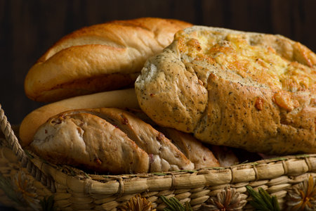 Basket with rustic spiced breads on wooden table. Dark background with space for copy.